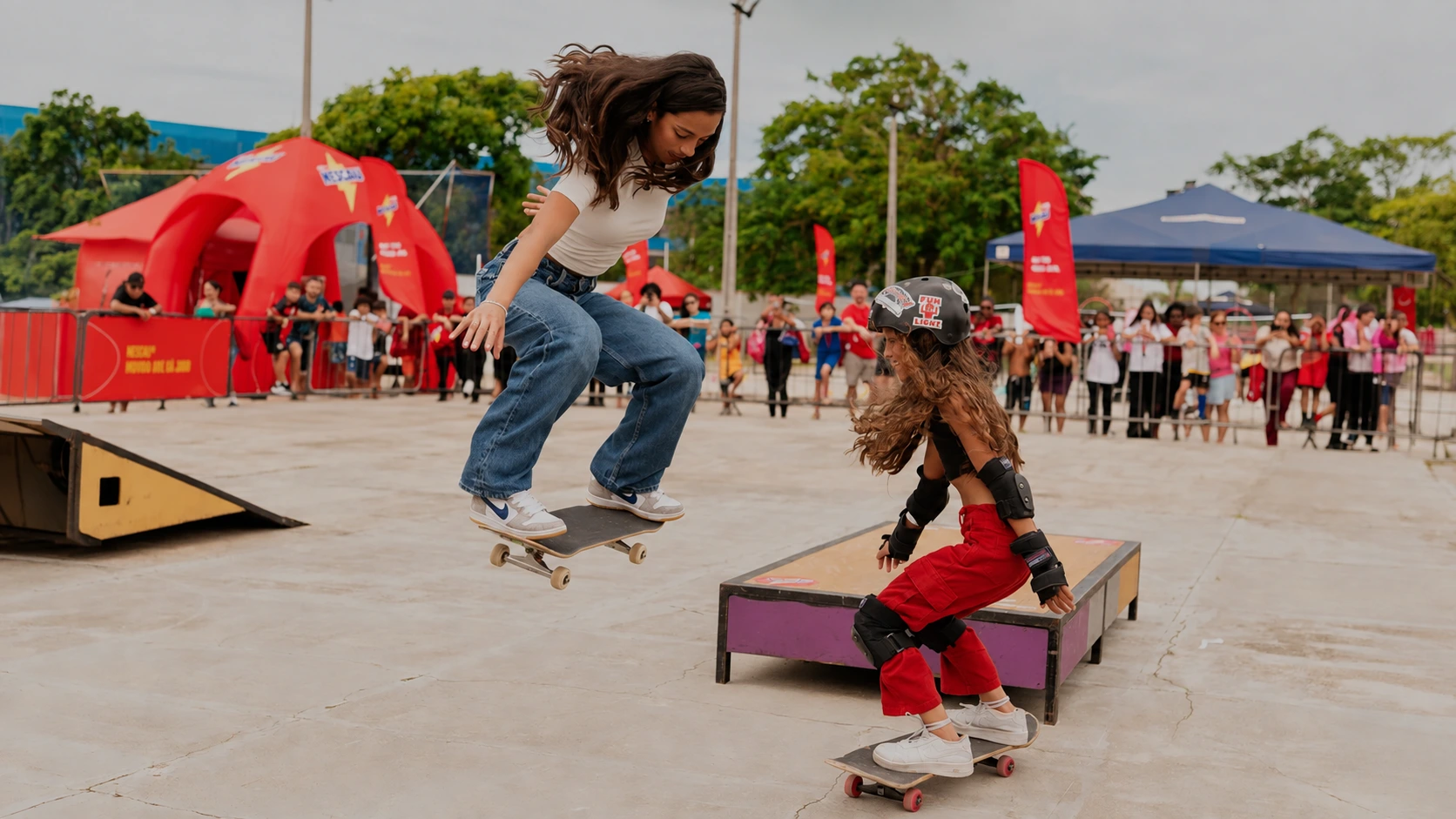 Duas meninas andando de skate em um evento da Liga Nescau.